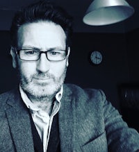 a man wearing glasses and a jacket